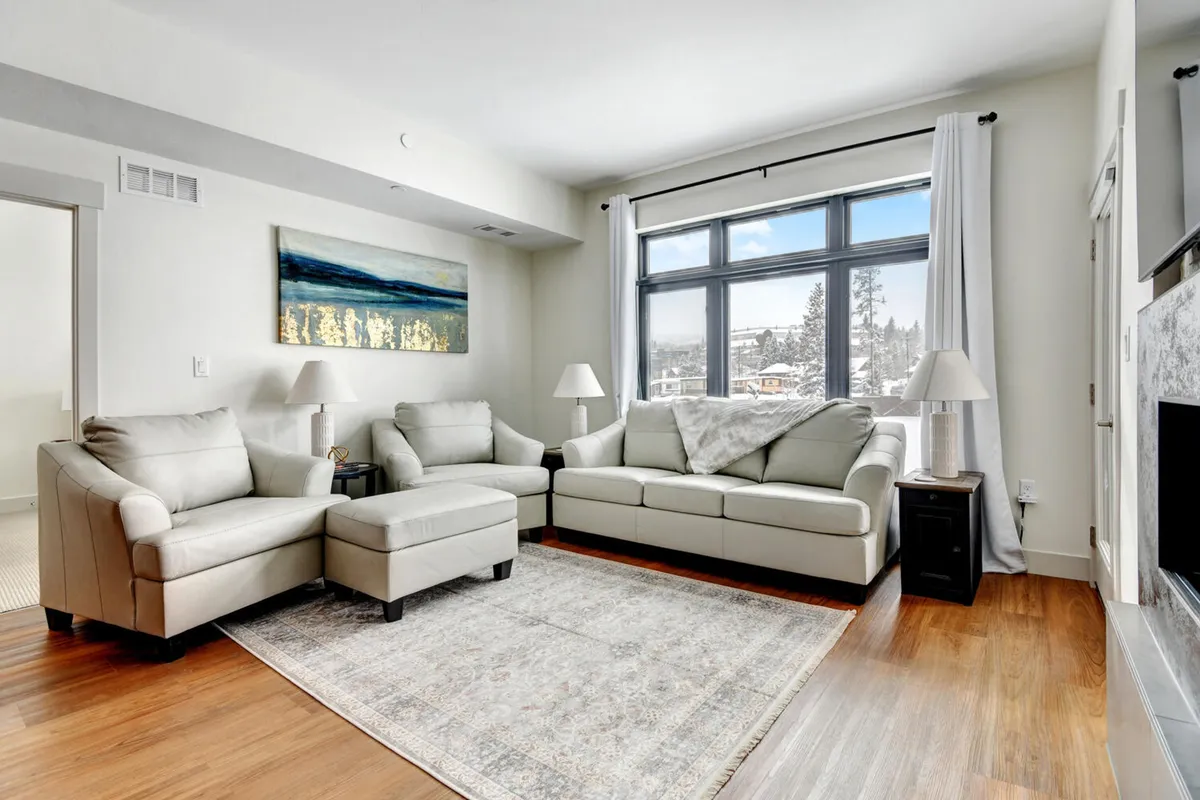 A cozy living room featuring a welcoming sofa set, colorful artwork on the wall, and expansive windows letting in natural light. The space is designed for relaxation, socializing, or winding down with a movie night—ideal for groups utilizing the queen sleeper sofa.