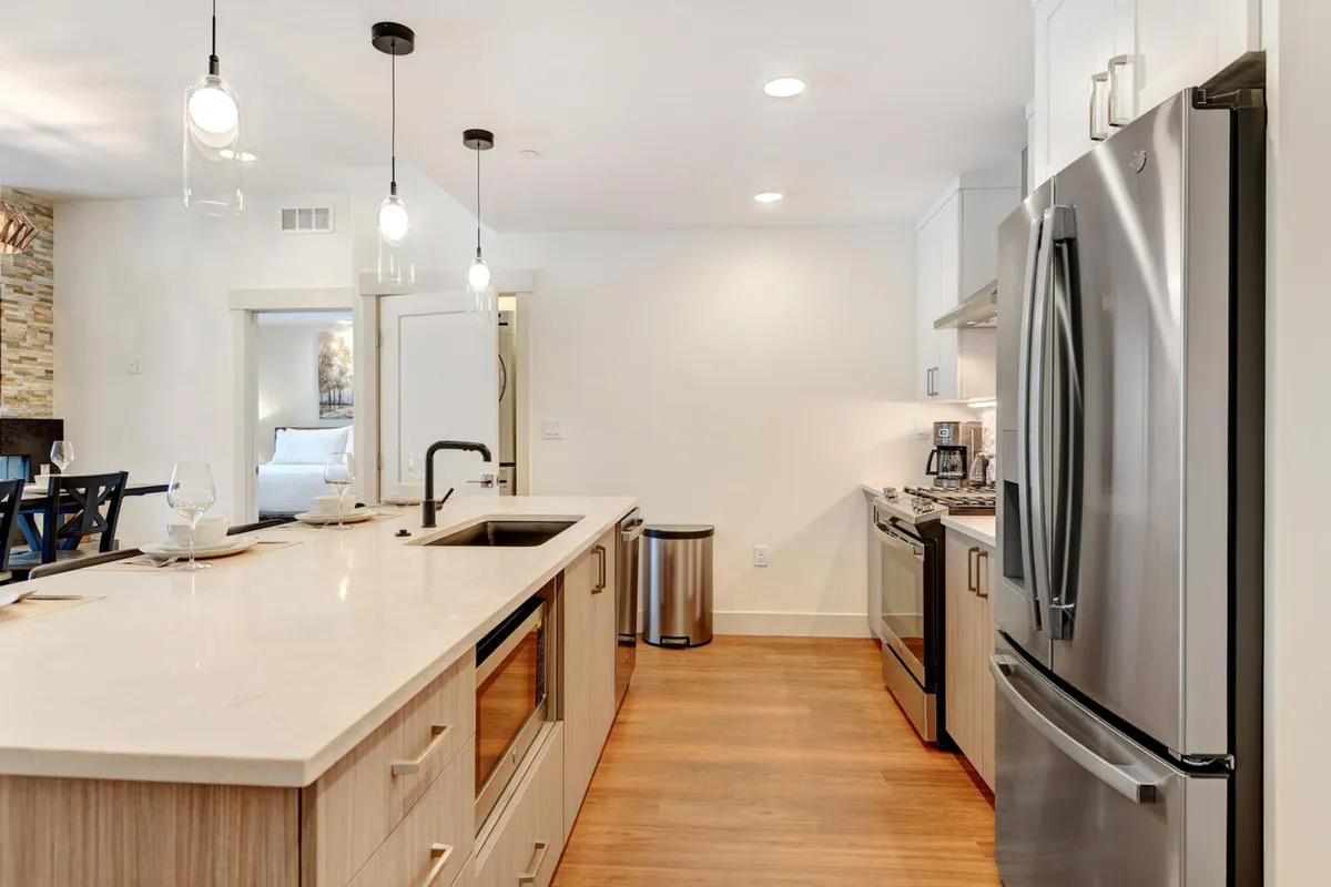 This photo zeroes in on the gourmet kitchen, with its inviting kitchen island, gleaming stainless steel appliances, and modern pendant lighting. The setup is perfect for cooking, entertaining, and enjoying family or group breakfasts.