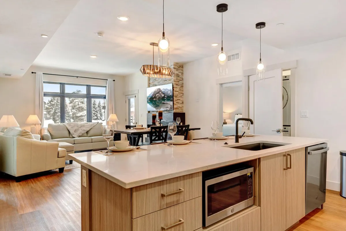 An open kitchen and dining area are featured here, with an expansive kitchen island perfect for gourmet cooking. The living room seating is arranged to foster socializing, while large windows brighten the space. The mood is warm and inviting, ideal for entertaining or unwinding after a day of adventure.